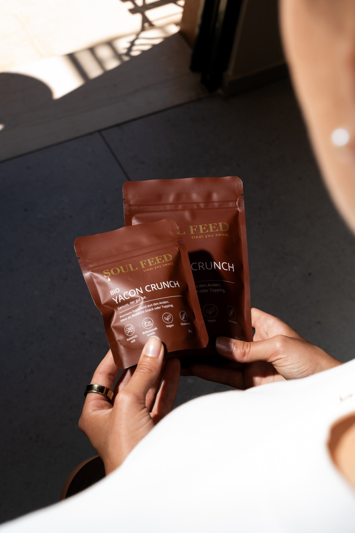 Eine Frau hält beide Verpackungsgrößen von Soul Feed Yacon Crunch in den Händen.